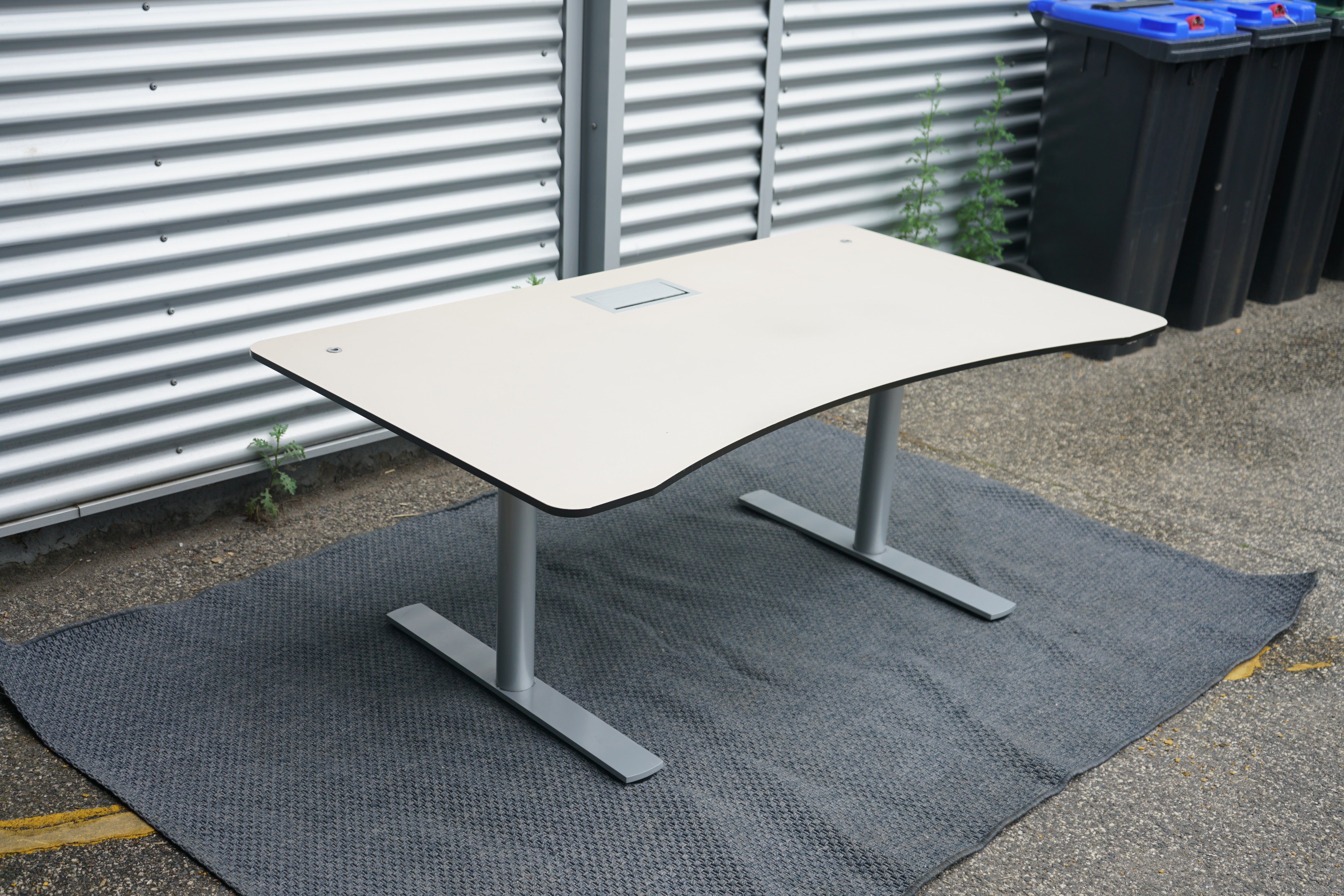 Paustian hæve-sænkebord i beige med lys linoleum set i skrå vinkel, 160x90 cm med elegant mavebue.